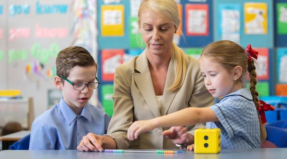 A teacher with students playing with blocks to count.