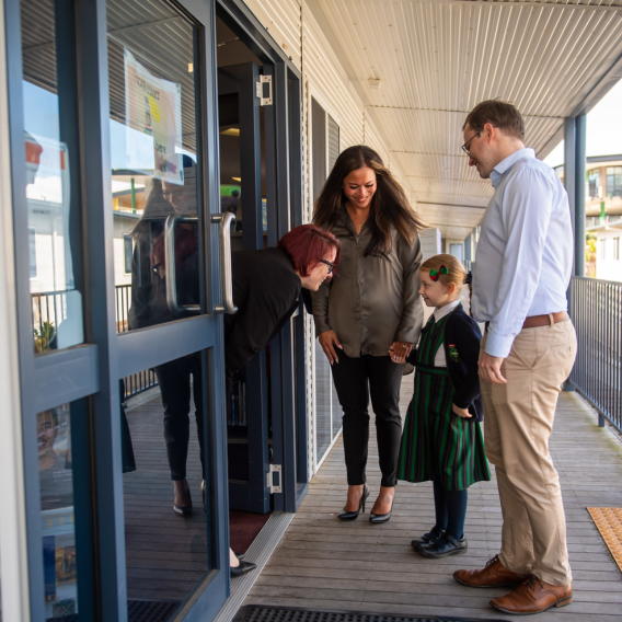 Parents dropping their child at the Catholic school classroom to meet the teacher.