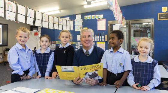 A teacher reading a book to primary school students.