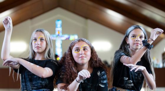 Three Aboriginal girls doing a cultural dance in the Catholic church.