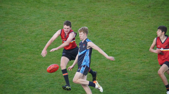 Two teenage boys playing Australian football.
