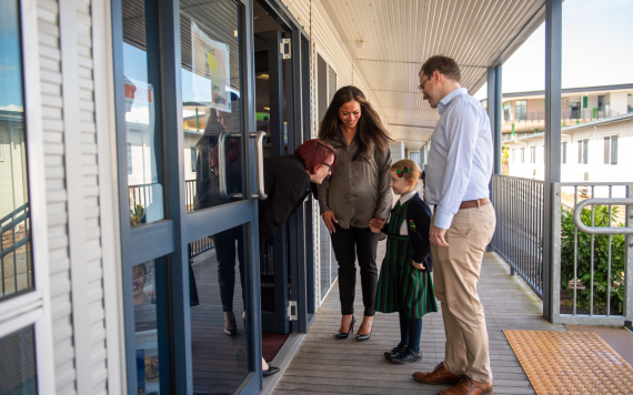 Parents dropping their child at the Catholic school classroom to meet the teacher.